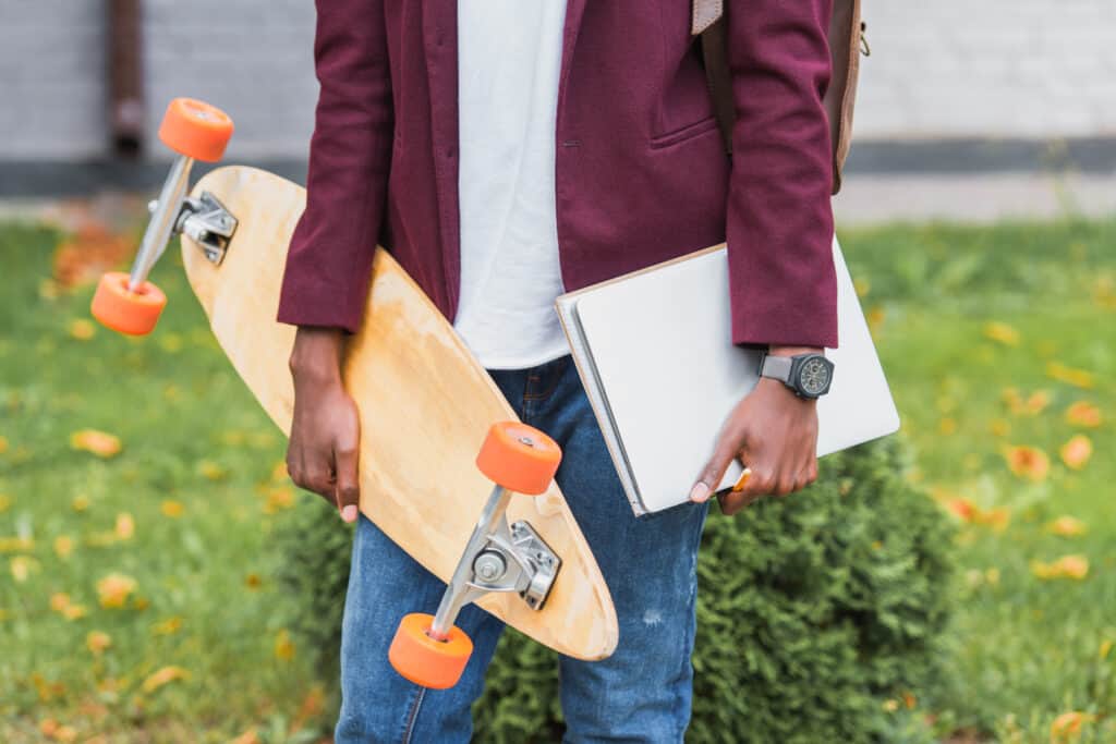 black man holding skateboard and notebook