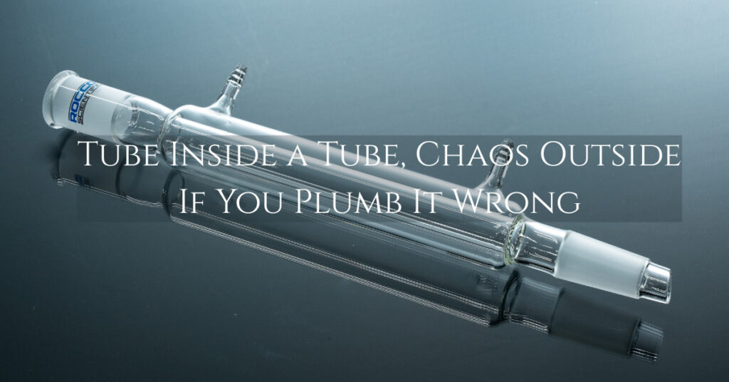 Liebig condenser in a laboratory setup showing inner tube and outer water jacket, with hoses attached for coolant flow during distillation and reflux.