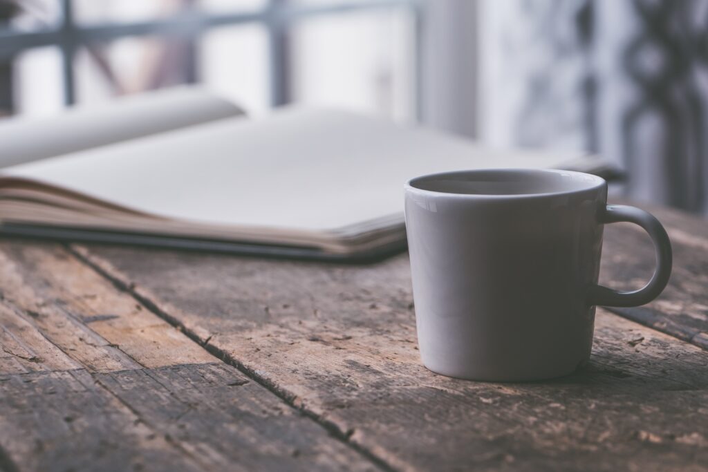 Open notebook and coffee mug on a wooden table, representing a pause to consider possible causes of brain fog