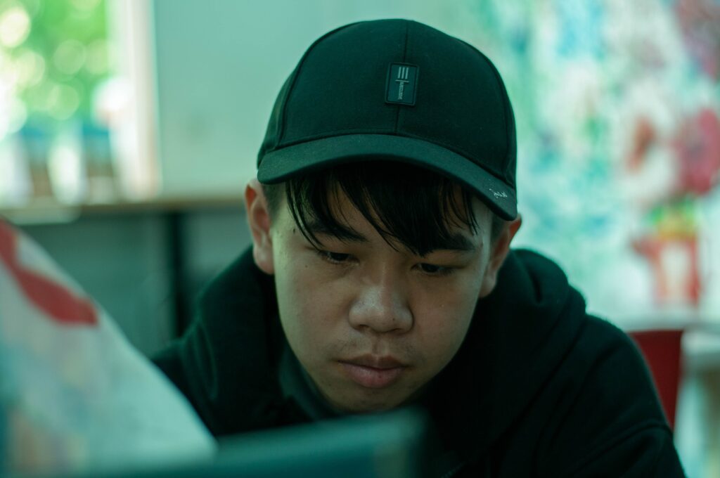 Man wearing a black cap leaning forward and looking down at a screen.